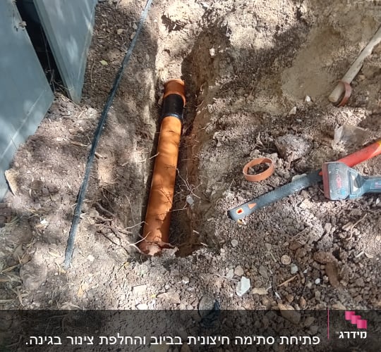 צינור כתום באדמה עם כלי עבודה לידו